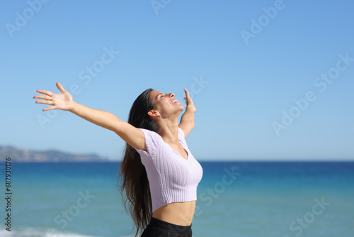 Joyful casual woman on the beach stretching arms