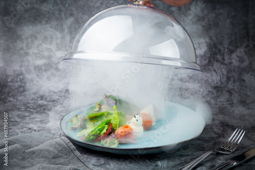 salad of leaves of different types of lettuce and fish rolls under a glass cover