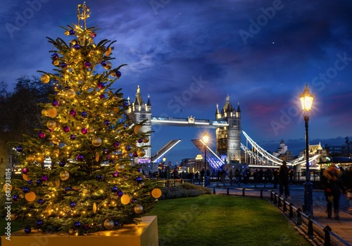 A beautiful Christmas Tree in front of the defocussed Tower Bridge of London, England, during an advent winter night