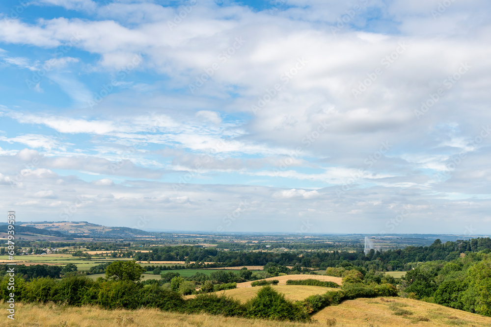 Panoramic view from a hill over the Cotswolds landscape near Stanway, Cheltenham, UK, with visible worlds highest gravity fountain against white clouded blue sky
