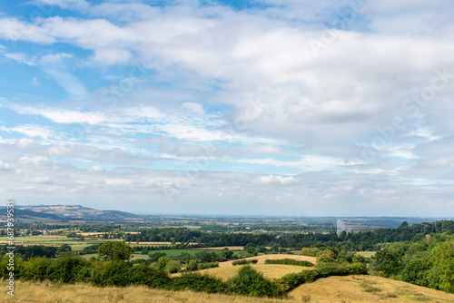 Panoramic view from a hill over the Cotswolds landscape near Stanway  Cheltenham  UK  with visible worlds highest gravity fountain against white clouded blue sky