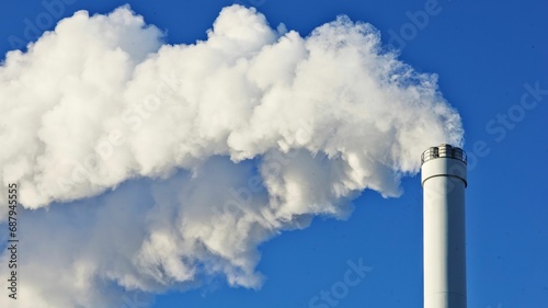 white smoke from a chimney spewing out into the blue sky