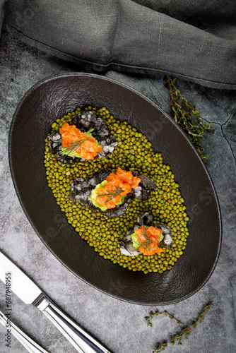 black caviar, red fish and wassabi on a plate with peas, top view photo