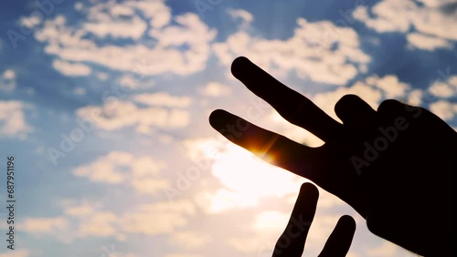 Silhouettes of four hands are showing victory sign, gesture of peace against the sunset or sunrise sky - close up, sun lens flare. Unity, harmony, friendship and positive concept photo
