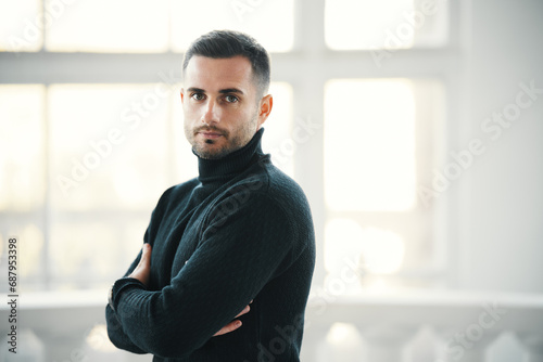 Fotografia Confident handsome man in a black turtleneck stands with arms crossed