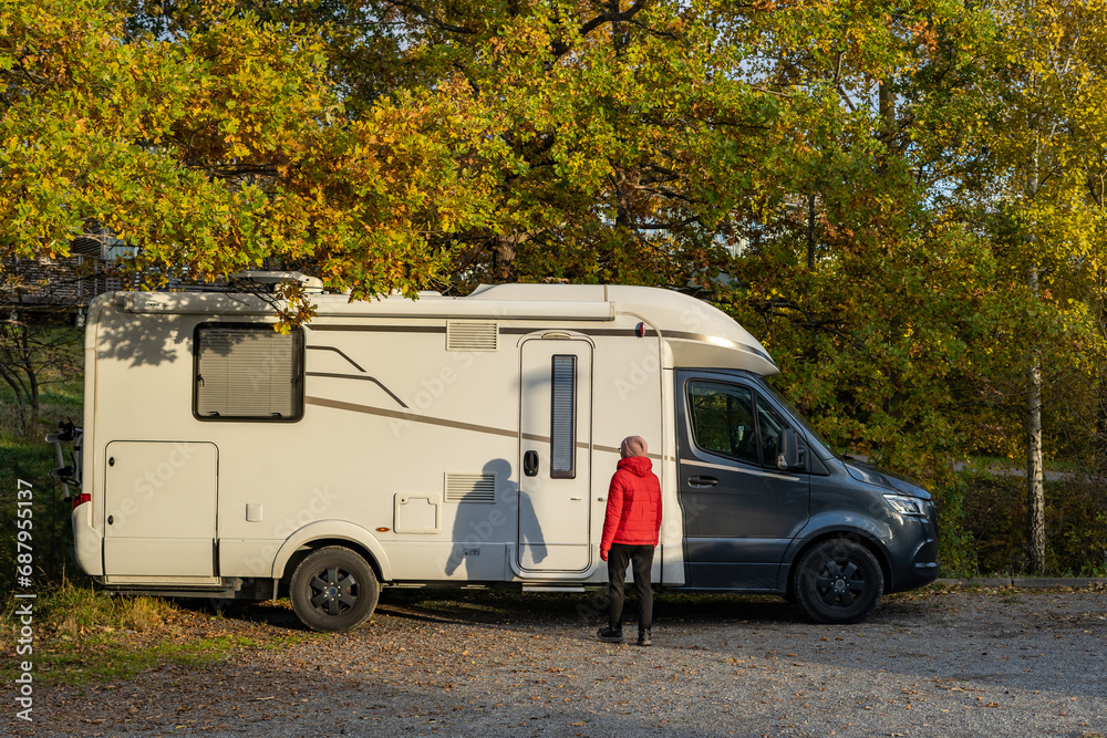 Naklejka premium Caravan travel trailer RV motor home camper. Car vehicle journey. Tourism Summer vacation holidays activity trip to Europe. A woman gets into a car for travelling. House on wheels concept.