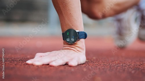 Athletic man training on red running track with smartwatch display tracking ECG, heart rate and training progress photo