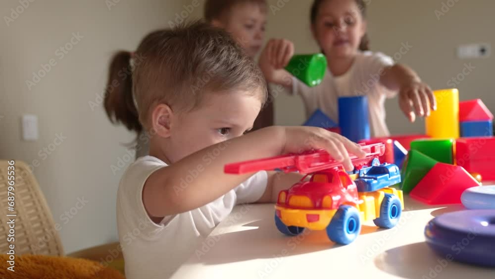kids girl and baby boy play in kindergarten. a group of children play toys cubes indoor and cars on the table in kindergarten. happy family preschool education concept. nursery baby toddler home kids girl and baby boy play in kindergarten. a group of children play toys cubes indoor and cars on the table in kindergarten. happy family preschool education concept. nursery baby toddler home