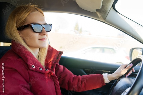 Portrait of a young woman in sunglasses driving a modern car. © makedonski2015