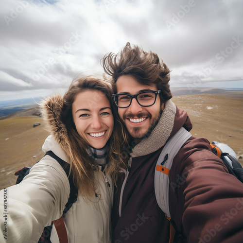 Cute couple of young people smiling and enjoying vacations trip together walking and trekking in mountains. Cheerful man and woman in love taking selfie #687967387