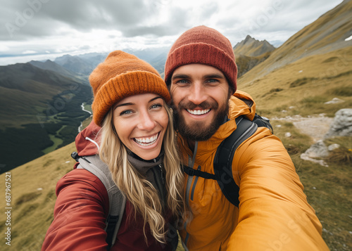 Cute couple of young people smiling and enjoying vacations trip together walking and trekking in mountains. Cheerful man and woman in love taking selfie #687967521