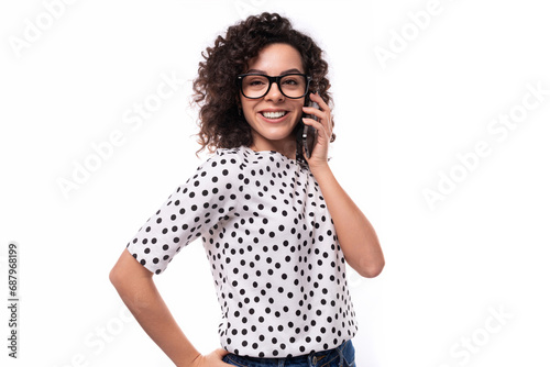 a young well-groomed slender lady with black curly hair in a polka-dot blouse speaks on the phone photo