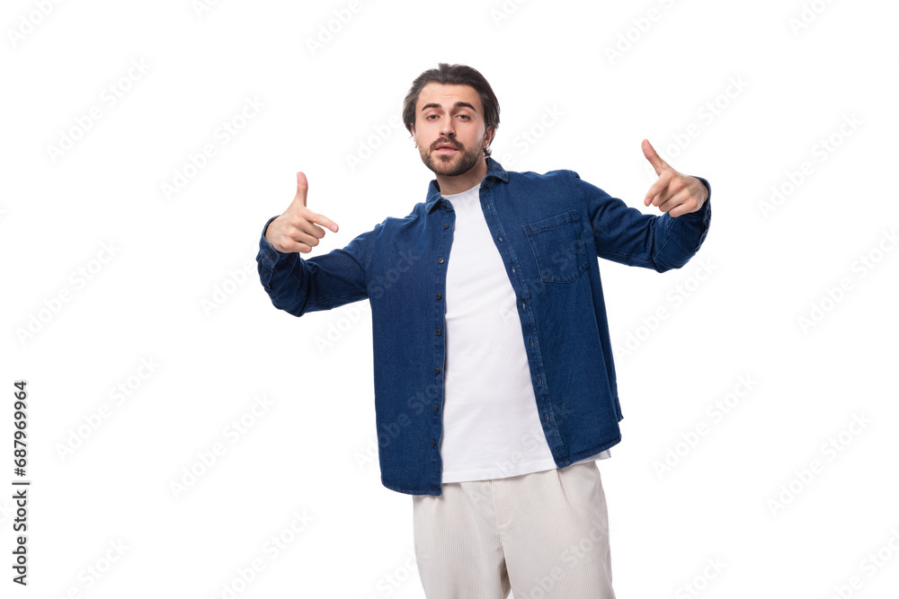 young handsome caucasian man with black hair is dressed in a blue shirt and light trousers on a white background young handsome caucasian man with black hair is dressed in a blue shirt and light trousers on a white background