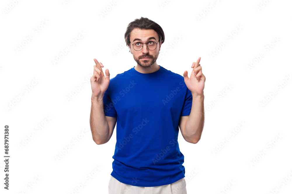 young caucasian brunette man with stylish hairstyle and beard crossed his fingers and hopes young caucasian brunette man with stylish hairstyle and beard crossed his fingers and hopes