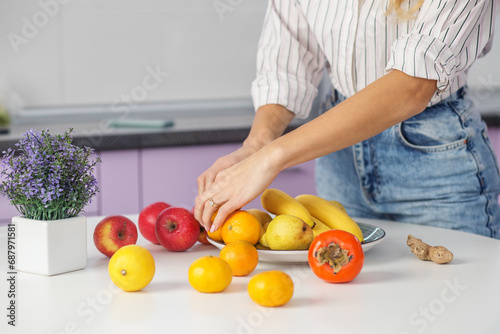 Organic food. Woman puts fruit on plate in kitchen. Diet and healthy eating concept.