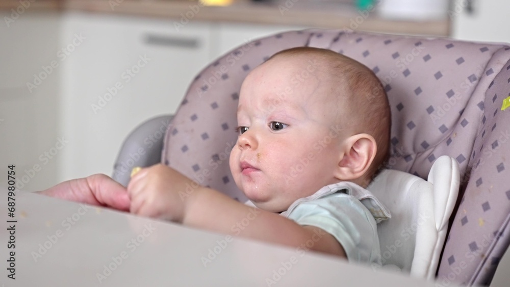 baby boy eats lunch at a feeding table in the kitchen. happy family child dream concept. mother feeds the baby in the kitchen. Baby child eats lunch in lifestyle the kitchen baby boy eats lunch at a feeding table in the kitchen. happy family child dream concept. mother feeds the baby in the kitchen. Baby child eats lunch in lifestyle the kitchen