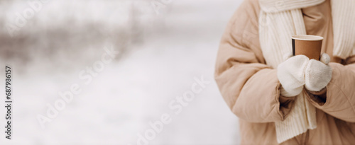 Female hands holding coffee hot drink cup and enjoys winter weather at snowy street copy space photo