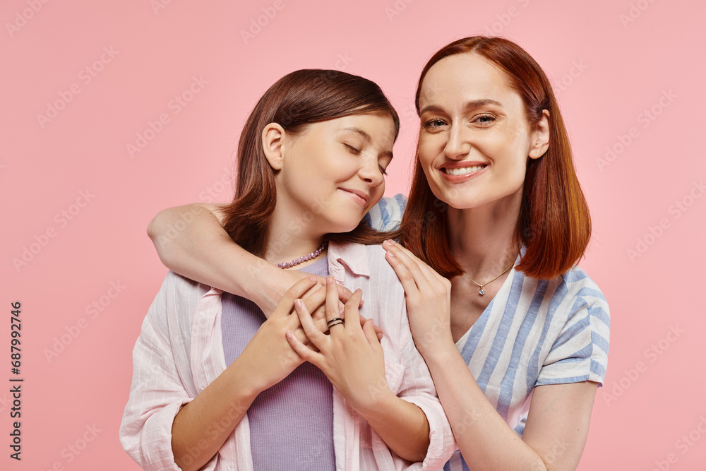 excited and inspired woman embracing teenage girl on pink backdrop, unity of mother and daughter excited and inspired woman embracing teenage girl on pink backdrop, unity of mother and daughter