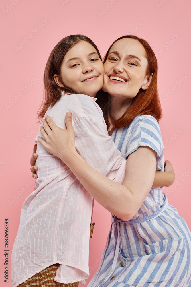 joyful woman with teenage daughter in stylish casual attire embracing and looking at camera on pink joyful woman with teenage daughter in stylish casual attire embracing and looking at camera on pink