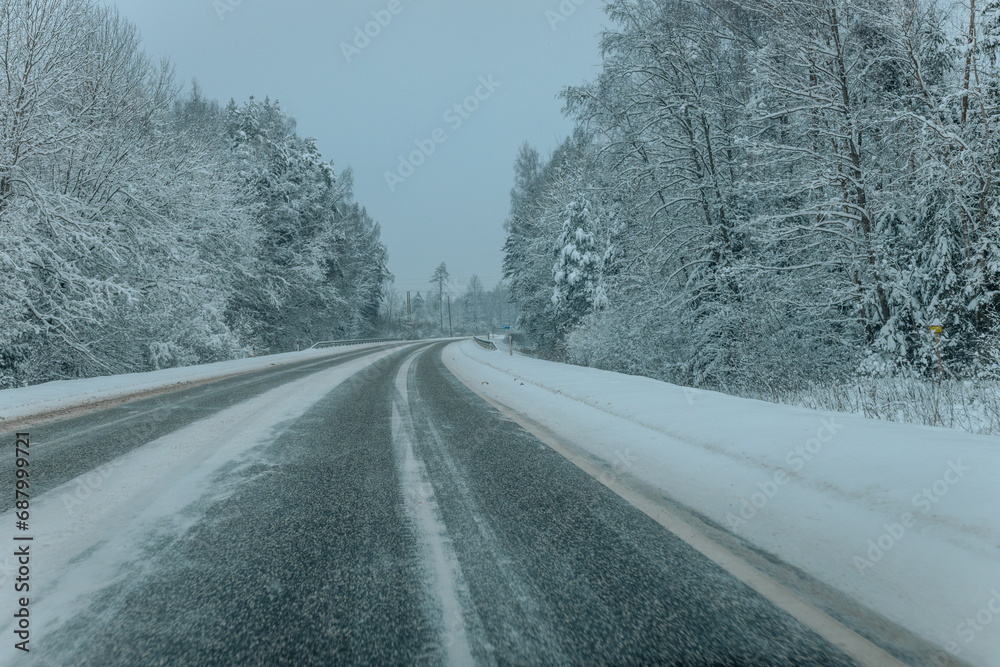 A Wintry Path Through a Chilly Forest with Snow Covered Trees. Winter road through snowy forest, tree lined and cold temperature. A Wintry Path Through a Chilly Forest with Snow Covered Trees. Winter road through snowy forest, tree lined and cold temperature.