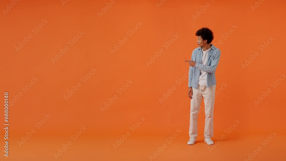 Stylish guy pointing with hands on empty orange background Stylish guy pointing with hands on empty orange background