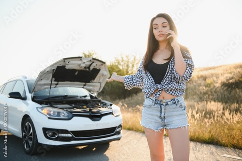 Young sexy woman with broken car calling on the cell phone.