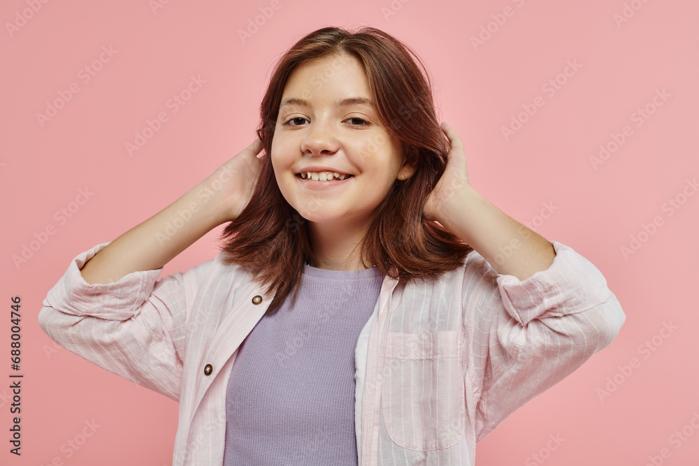 joyful and stylish preteen girl with healthy shiny hair smiling at camera on pink backdrop in studio joyful and stylish preteen girl with healthy shiny hair smiling at camera on pink backdrop in studio