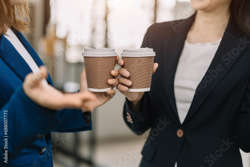 female colleague of half Asian descent holds a cup of coffee and smiles happily.