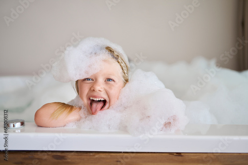 Playful girl covered in soap suds and sticking out tongue photo