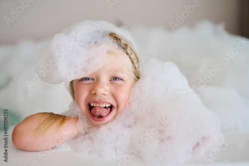 Cheerful girl covered in soap suds and sticking out tongue photo