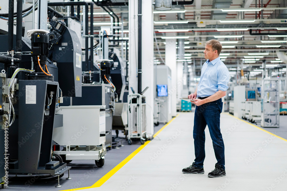 Businessman using digital tablet on shop floor in a factory Businessman using digital tablet on shop floor in a factory