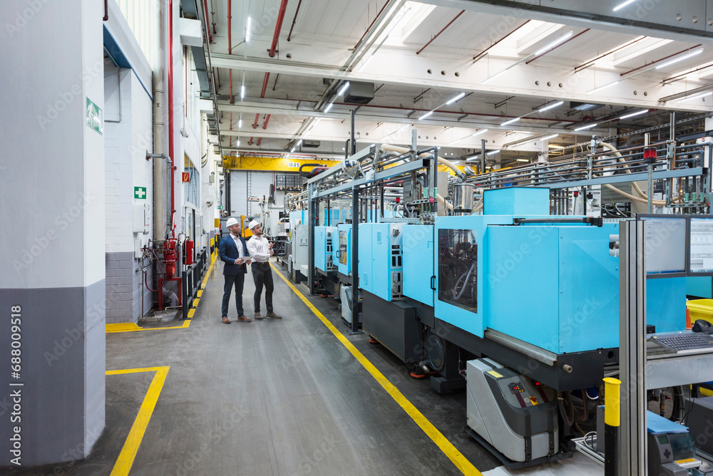 Manager and coworker inspecting machines at factory