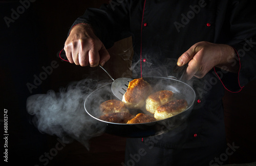 Fototapeta Naklejka Na Ścianę i Meble -  The chef is preparing oladki in a frying pan. The concept of preparing Ukrainian national dish or bliny in the kitchen. Black space for recipe or menu
