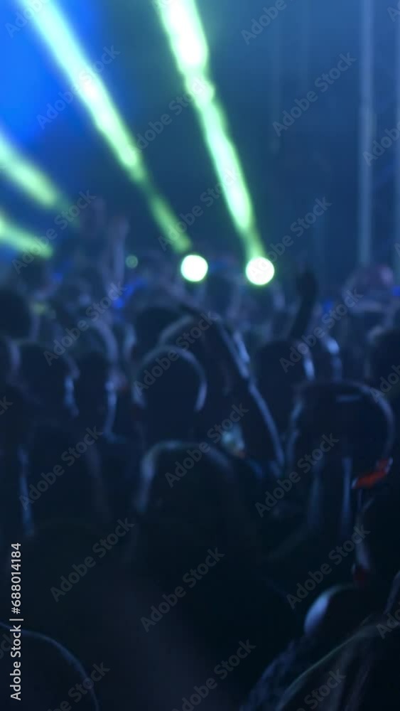 Young People are celebrating music concert.  Fans jump and raise their hands up. The crowd of excited fans applauding - vertical video for reel and story
