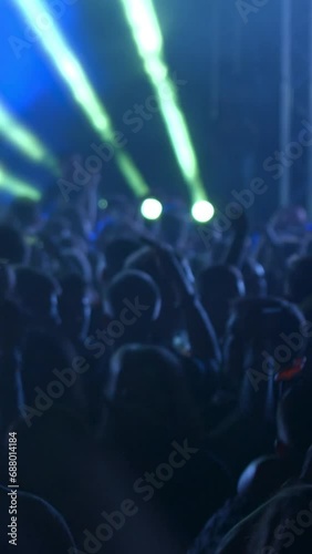 Young People are celebrating music concert.  Fans jump and raise their hands up. The crowd of excited fans applauding - vertical video for reel and story