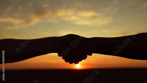 Handshake of two businessmen colleagues against background of sun, silhouette of two hands in nature. Business through handshake. Conclusion of deal. Handshake agreed. Business people shake hands, sky