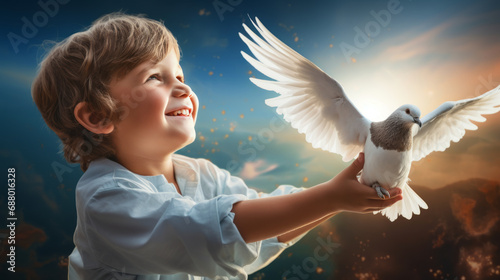 child holds a beautiful white dove in his hands and looks up at a beautiful blurred background of clouds and glare. Happy baby and dove of peace.