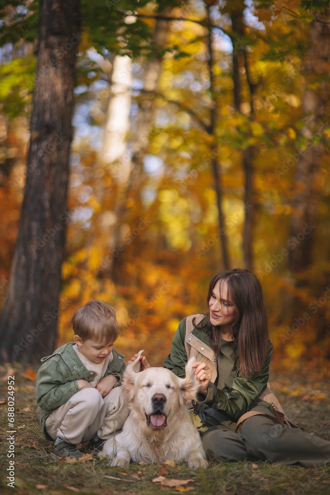 Smiling beautiful family of four walking in the park with a happy golden retriever and enjoying the beautiful autumn nature. Smiling beautiful family of four walking in the park with a happy golden retriever and enjoying the beautiful autumn nature.