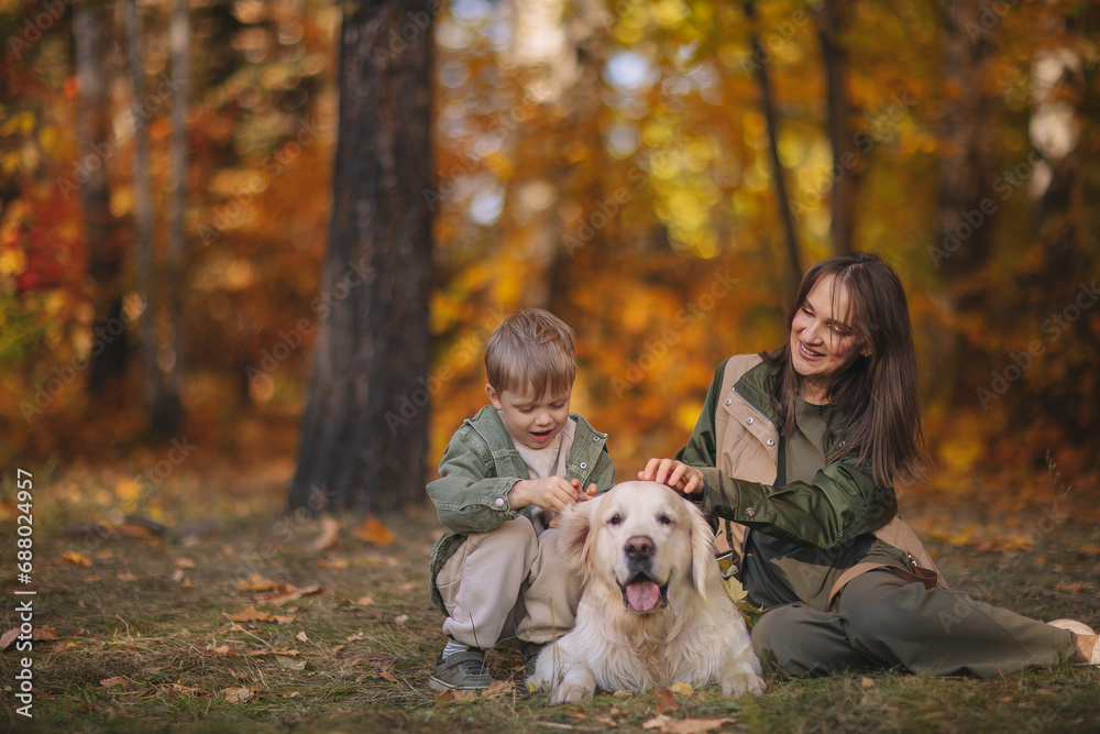 Smiling beautiful family of four walking in the park with a happy golden retriever and enjoying the beautiful autumn nature. Smiling beautiful family of four walking in the park with a happy golden retriever and enjoying the beautiful autumn nature.