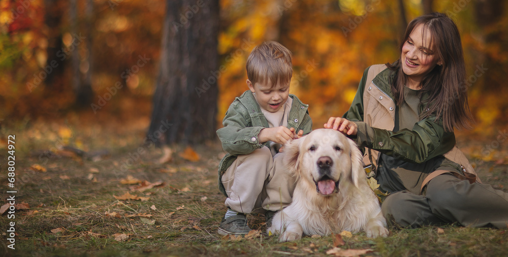 Smiling beautiful family of four walking in the park with a happy golden retriever and enjoying the beautiful autumn nature. Smiling beautiful family of four walking in the park with a happy golden retriever and enjoying the beautiful autumn nature.