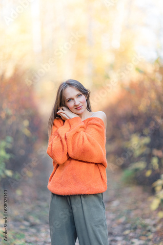 Portrait of an attractive brunette woman walking in the park at fall on a sunny day and smiling. The face of a happy beautiful woman in autumn outdoor.