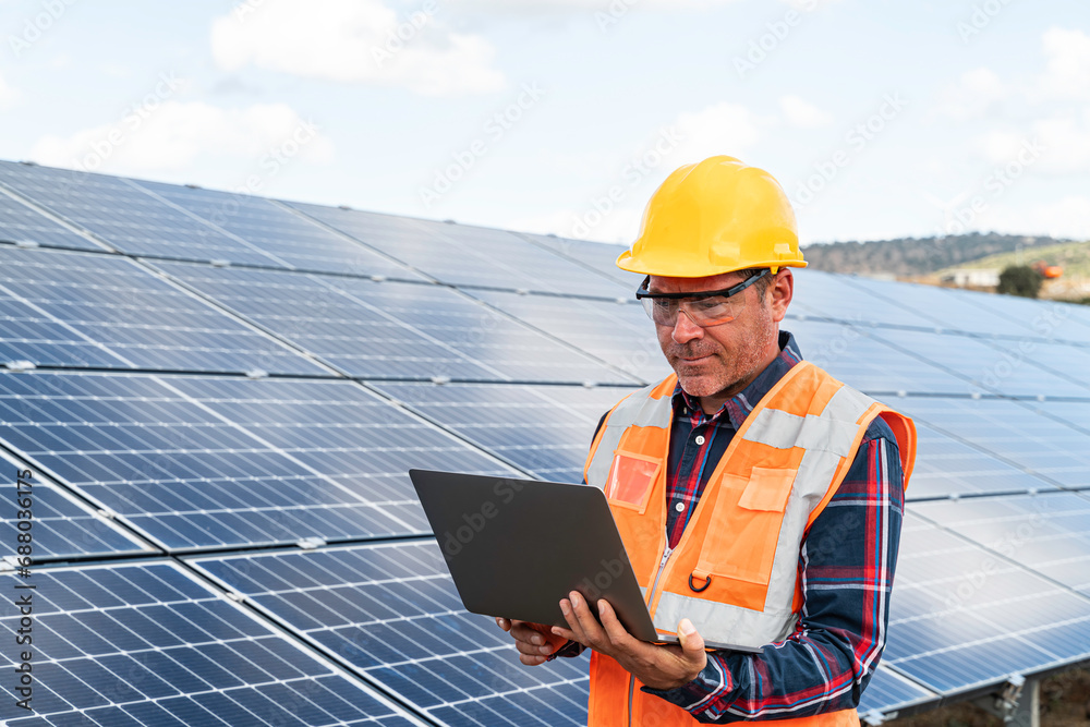 Portrait of male manager engineer in safety helmet checking with computer an operation of solar panel system at solar station Portrait of male manager engineer in safety helmet checking with computer an operation of solar panel system at solar station