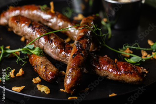 Grilled sausage on a dark plate with sauce