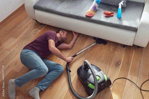 Man cleaning apartment with vacuum cleaner.