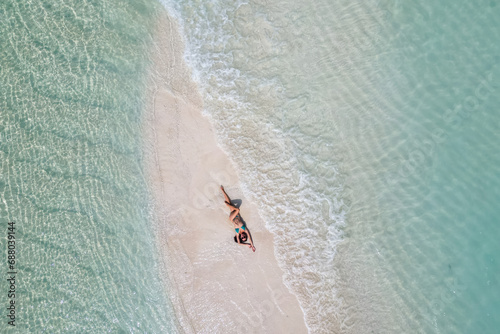 young woman tanning sunbathing woman wearing bikini at the beach on a white sand from above view from drone