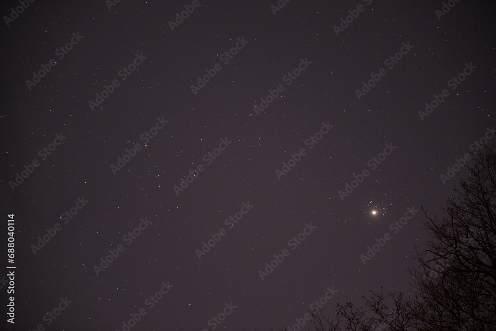 The planet Venus in the starry night sky in conjunction with the Pleiades Constellation. The group of stars The seven sisters observed from a dark place