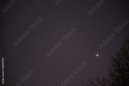 The planet Venus in the starry night sky in conjunction with the Pleiades Constellation. The group of stars The seven sisters observed from a dark place