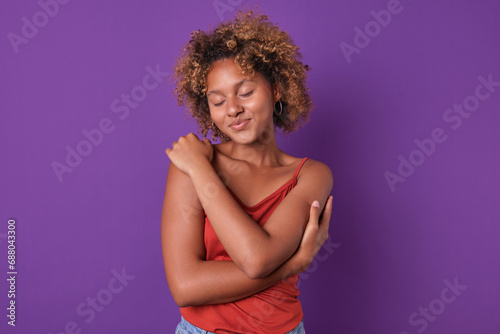Photos Young happy teenage African American woman dressed in casual clothes hugs hersel