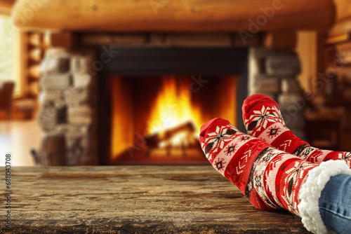 Woman legs with warm winter socks. Home interior with fireplace and empty space for your decoration. Mockup background and december time. Cold winter and new year. 