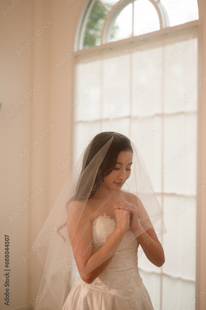 Beautiful bride in wedding dress covered by white veil, folding her arms and praying on ceremony, Love and marriage concept Beautiful bride in wedding dress covered by white veil, folding her arms and praying on ceremony, Love and marriage concept